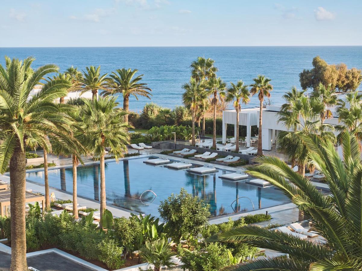 Een luchtfoto van een resort met palmbomen en een zwembad. bij Grecotel LUXME White in Adelianos Kampos
