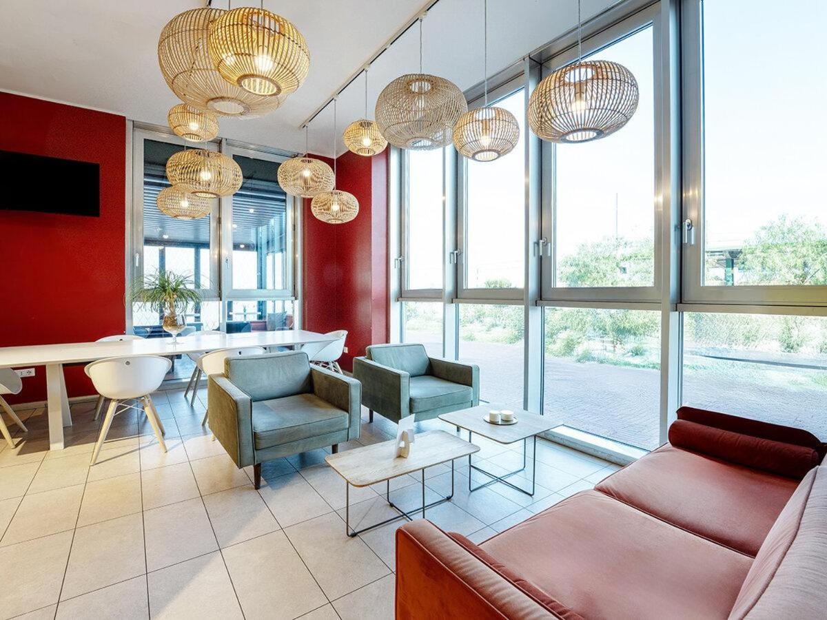 een woonkamer met een bank, stoelen en ramen bij B&B Hotel Roma Fiumicino Aeroporto Fiera 1 in Fiumicino