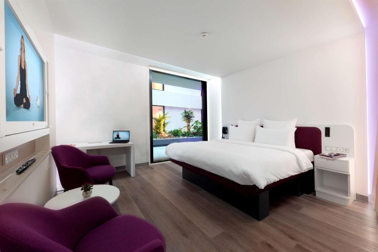 een slaapkamer met een groot bed en een paarse stoel bij YOTELAIR Istanbul Airport, Duty free - International Transit ar