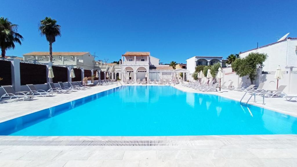 een groot zwembad met ligstoelen en blauw water bij Ionian Blue Beach Hotel - Adults Only in Kavos