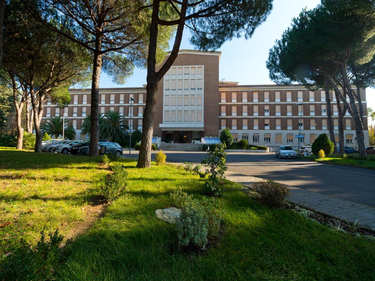 een groot gebouw met een boom ervoor aan een straat bij Ele Green Park Hotel Pamphili in Rome