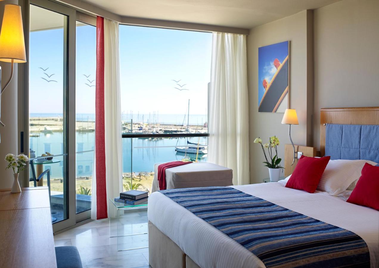 een hotelkamer met een bed en een groot raam bij Kyma Suites Beach Hotel in Rethimnon