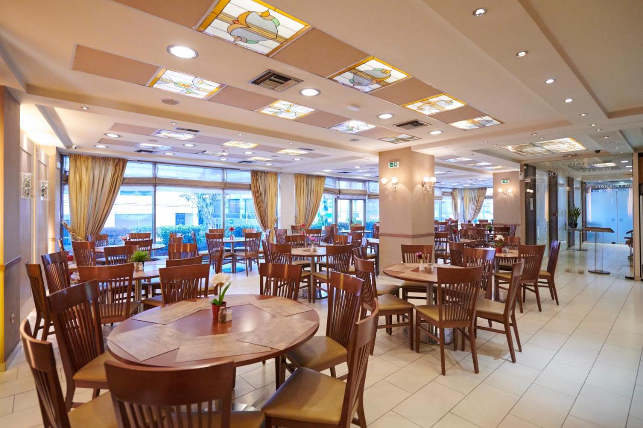 een restaurant met houten tafels en stoelen en ramen bij Crystal City Hotel in Athene