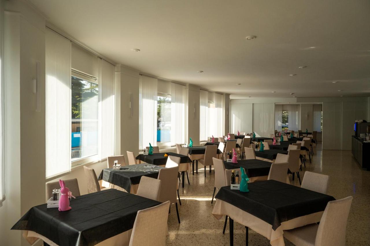 een eetkamer met tafels en stoelen met roze servetten erop bij Hotel Angelini in Nago-Torbole