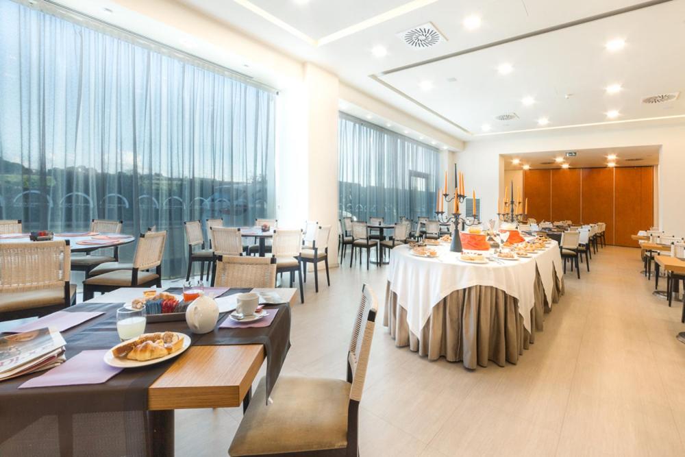 een eetkamer met tafels en stoelen en grote ramen bij Poggio Del Sole Hotel in Contrada Cimillà